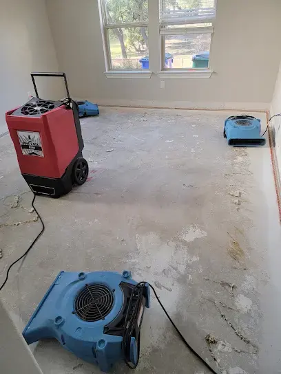 Dehumidifier and air mover drying a bare subfloor in a Leander home