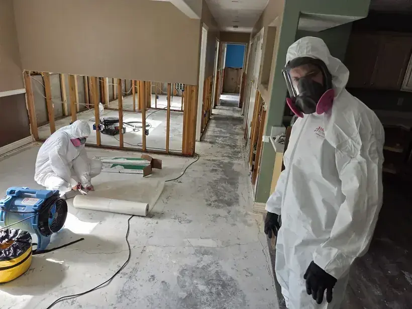 Technicians in protective suits cleaning a contaminated floor after a sewage backup